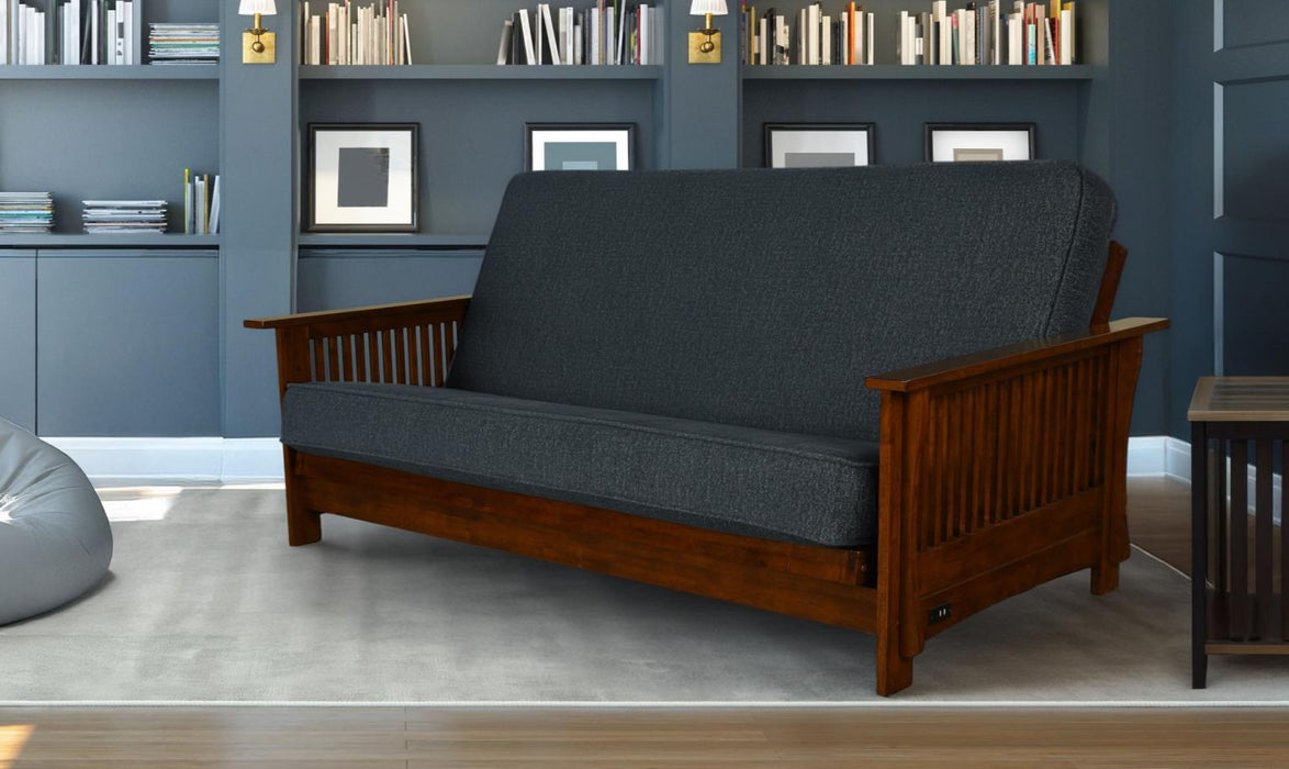 Dark blue futon sofa with wooden frame in a room with bookshelves and a rug.