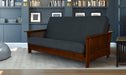 Dark blue futon sofa with wooden frame in a room with bookshelves and a rug.