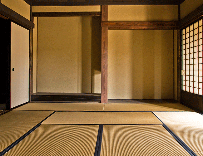Traditional Japanese Tatami Room with Tatami's covering the floor and soft amber lighting reflected on the walls coming in from the window