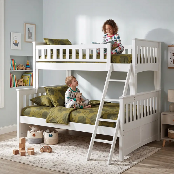 White bunk beds in a children's room. Bottom bunk is larger than the top bunk.  A little boy sits in his pajamas on the bottom bunk and a little girl sits reading a book in her pajamas on the top bunk.